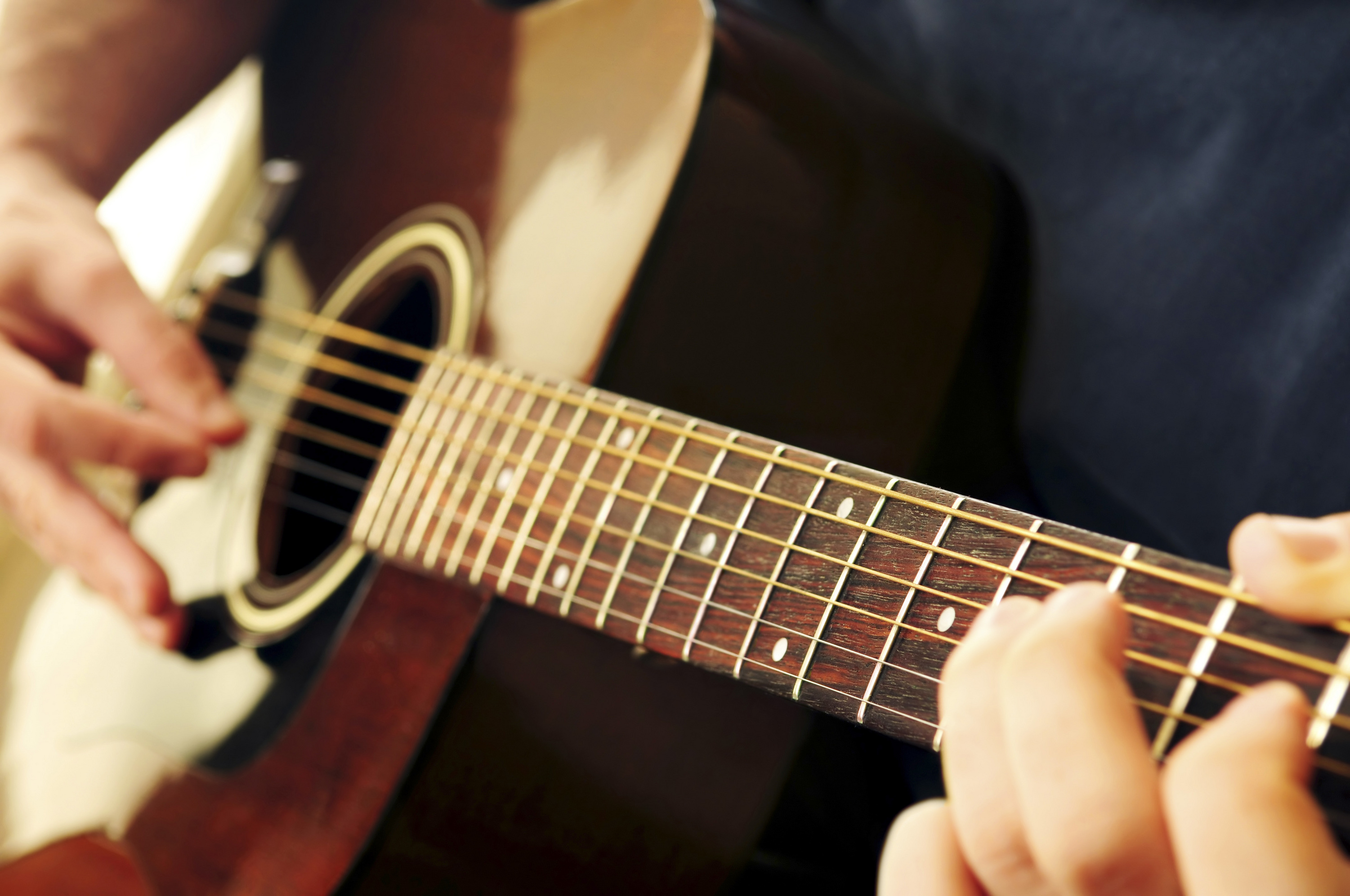 Hands of a person playing an acoustic guitar CSA Colégio Santo Antônio